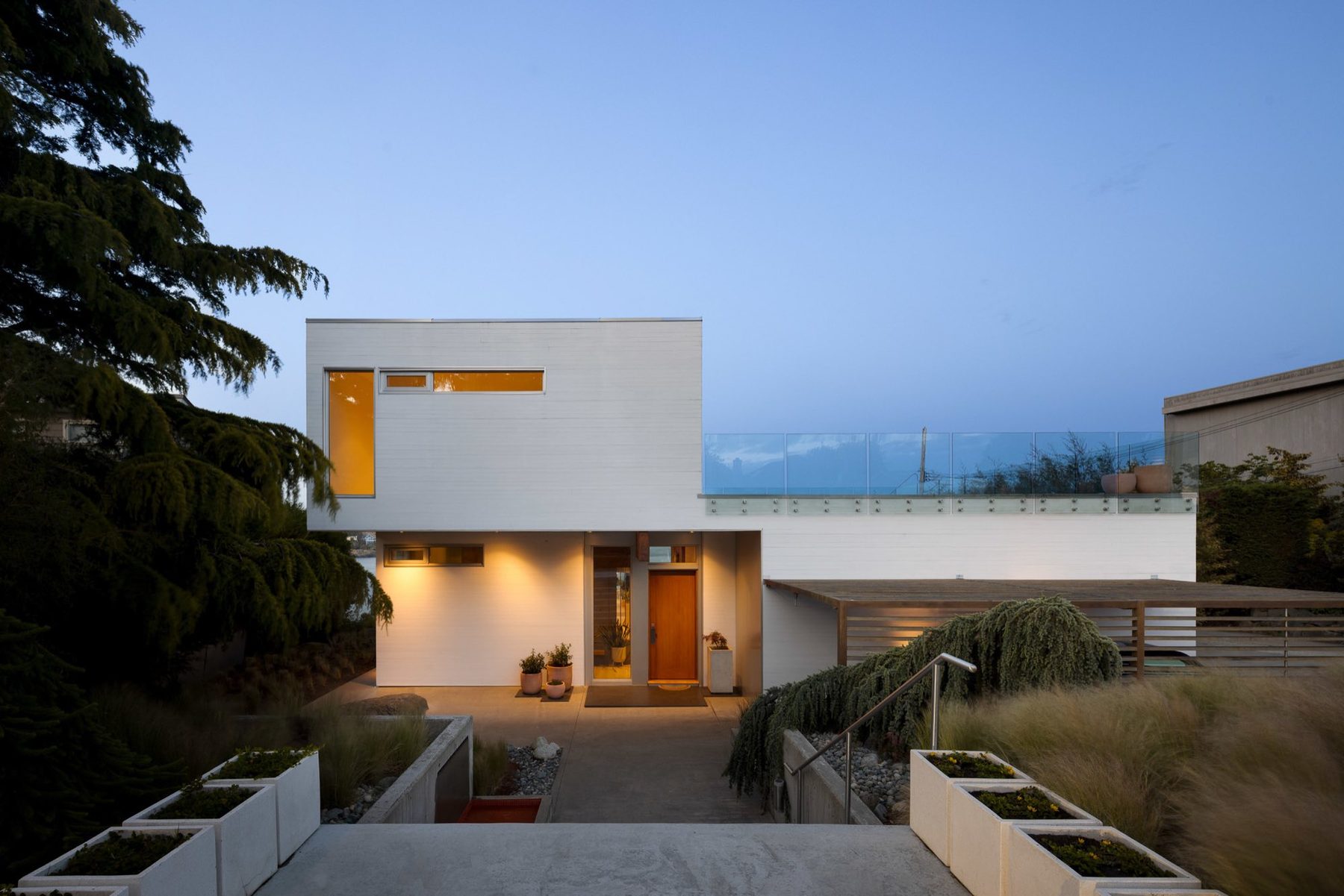 Cedar and white modern entry at blue hour, windows lit